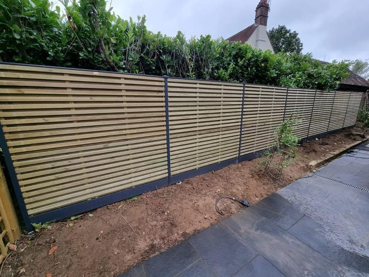 Horizontal slatted fence panels with dark posts beside a garden path